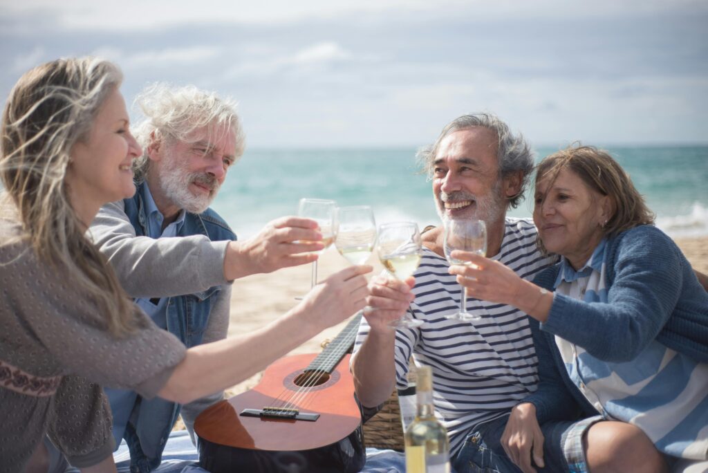 Senior friends enjoying wine on a beach vacation in Portugal.